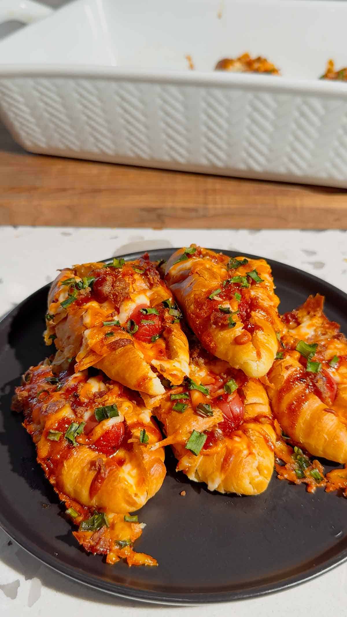 Looking for the ultimate easy party appetizer? These Cheesy Bacon Mini Croissant Dogs are loaded with smoky bacon, melty cheddar cheese, cocktail wieners and BBQ sauce baked inside buttery mini croissants for the perfect bite-sized snack. This easy appetizer recipe is perfect for game day food, football parties, holiday appetizers, movie night snacks and fun family dinners. Using store bought mini croissants keeps this recipe quick, simple and packed with comfort food flavor. If you love pigs in a blanket, cheesy hot dog recipes, bacon appetizers, easy finger foods and crowd pleasing party snacks, these loaded mini croissant dogs are a must-try recipe everyone will be grabbing straight from the pan for seconds.
