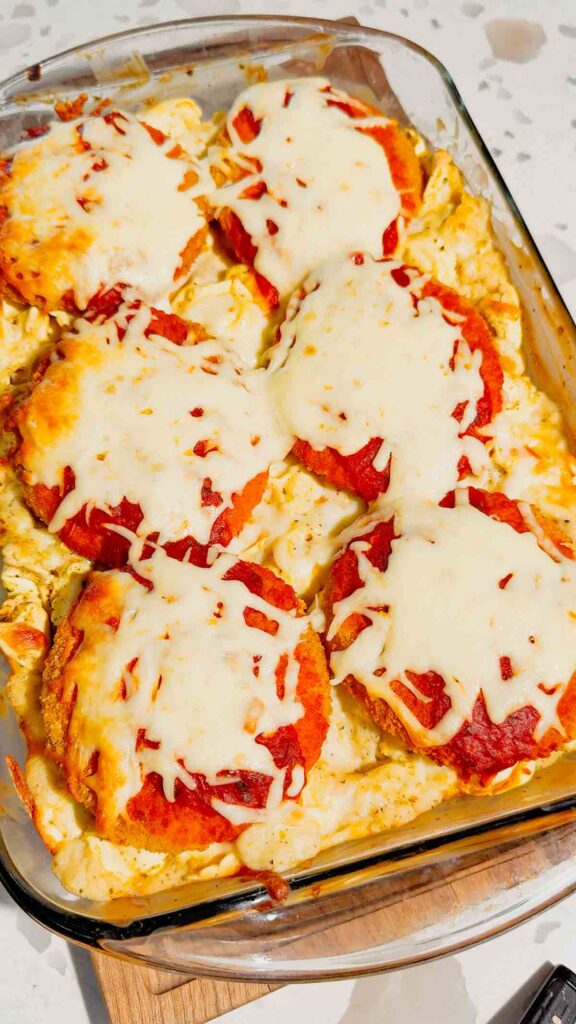 This Dump and Bake Chicken Parm Tortellini Alfredo is the ultimate easy comfort food dinner for busy weeknights, lazy dinners and family meals everyone will love. Made with refrigerated cheese and bacon tortellini, creamy jarred Alfredo sauce, crispy breaded chicken burgers, rich marinara sauce and gooey melted mozzarella, this baked pasta casserole comes together in one dish with almost no prep. If you love easy chicken parm recipes, dump dinners, baked tortellini recipes, cheesy pasta casseroles and simple family dinner ideas, this recipe is a must-try. Perfect for quick weeknight dinners, freezer meals, potlucks and cozy comfort food cravings, this creamy chicken parmesan tortellini bake is loaded with flavour, cheesy layers and hearty pasta goodness in every bite.