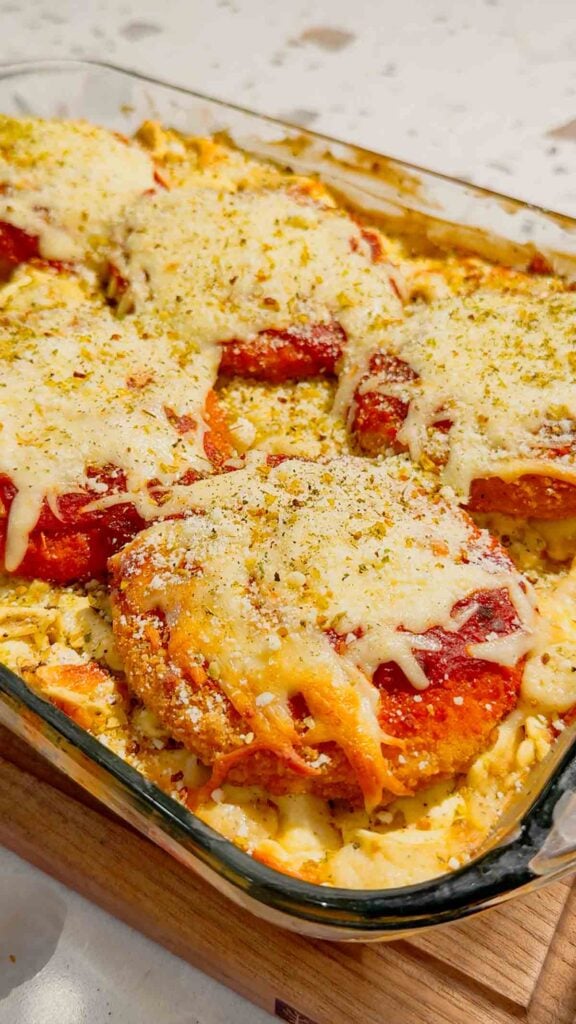 This Dump and Bake Chicken Parm Tortellini Alfredo is the ultimate easy comfort food dinner for busy weeknights, lazy dinners and family meals everyone will love. Made with refrigerated cheese and bacon tortellini, creamy jarred Alfredo sauce, crispy breaded chicken burgers, rich marinara sauce and gooey melted mozzarella, this baked pasta casserole comes together in one dish with almost no prep. If you love easy chicken parm recipes, dump dinners, baked tortellini recipes, cheesy pasta casseroles and simple family dinner ideas, this recipe is a must-try. Perfect for quick weeknight dinners, freezer meals, potlucks and cozy comfort food cravings, this creamy chicken parmesan tortellini bake is loaded with flavour, cheesy layers and hearty pasta goodness in every bite.