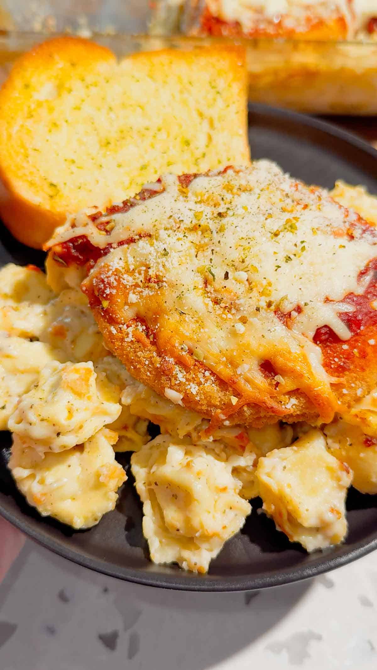 This Dump and Bake Chicken Parm Tortellini Alfredo is the ultimate easy comfort food dinner for busy weeknights, lazy dinners and family meals everyone will love. Made with refrigerated cheese and bacon tortellini, creamy jarred Alfredo sauce, crispy breaded chicken burgers, rich marinara sauce and gooey melted mozzarella, this baked pasta casserole comes together in one dish with almost no prep. If you love easy chicken parm recipes, dump dinners, baked tortellini recipes, cheesy pasta casseroles and simple family dinner ideas, this recipe is a must-try. Perfect for quick weeknight dinners, freezer meals, potlucks and cozy comfort food cravings, this creamy chicken parmesan tortellini bake is loaded with flavour, cheesy layers and hearty pasta goodness in every bite.