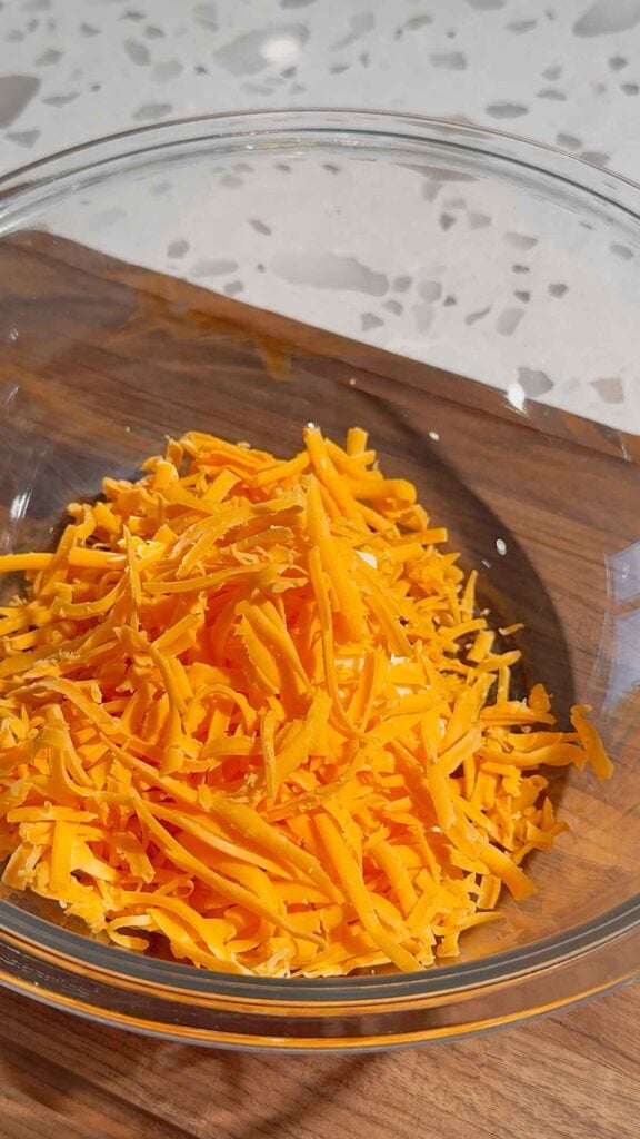 shredded cheddar cheese added to bowl with cream cheese and mayo