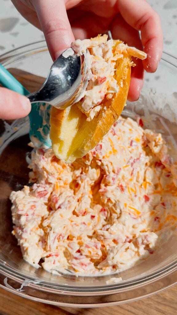 spooning pimento cheese mixture into the slit of a croissant