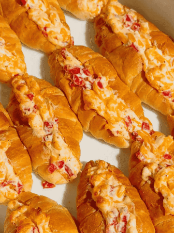 These Pimento Cheese Mini Croissants are the ultimate easy party appetizer for holidays, game day spreads, brunch tables and casual entertaining. Mini butter croissants are sliced open and stuffed with creamy homemade pimento cheese made with sharp cheddar, mayo, cream cheese and diced pimentos, then baked until warm, melty and golden brown. These cheesy baked croissant sandwiches are rich, buttery and packed with bold Southern-inspired flavour in every bite. Perfect for make ahead entertaining, easy finger foods, football snacks, brunch recipes, appetizer trays and quick baked party food ideas. If you love easy croissant recipes, cheesy appetizers, baked sandwiches and crowd pleasing snacks, this easy recipe is a must try.