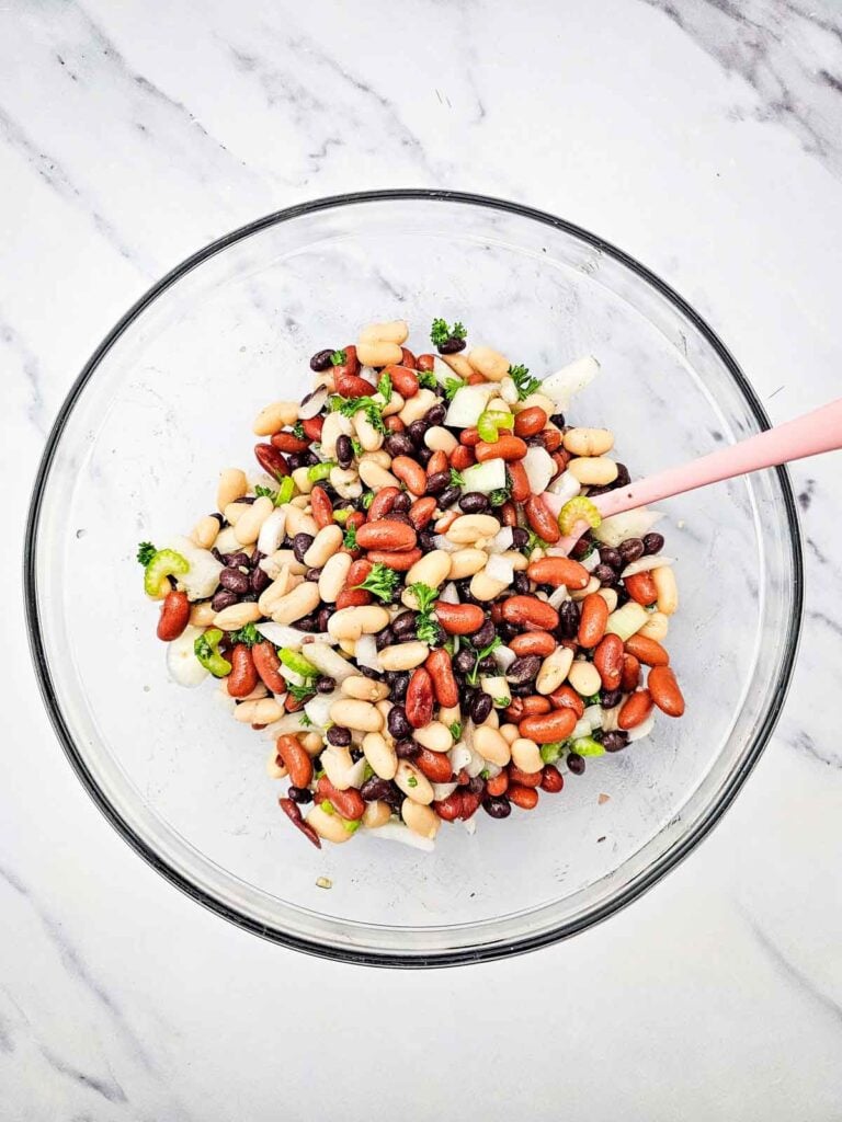 stirring dressing into 3 bean salad in a mixing bowl