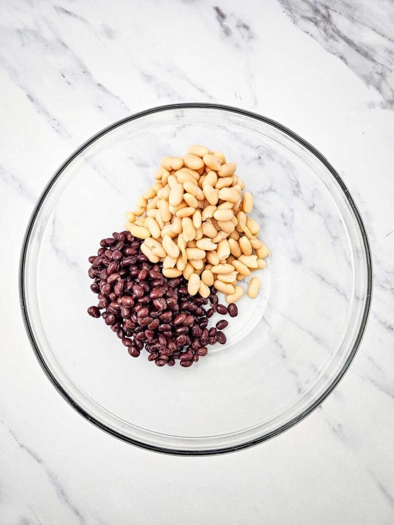 black beans and cannellini beans in a glass mixing bowl