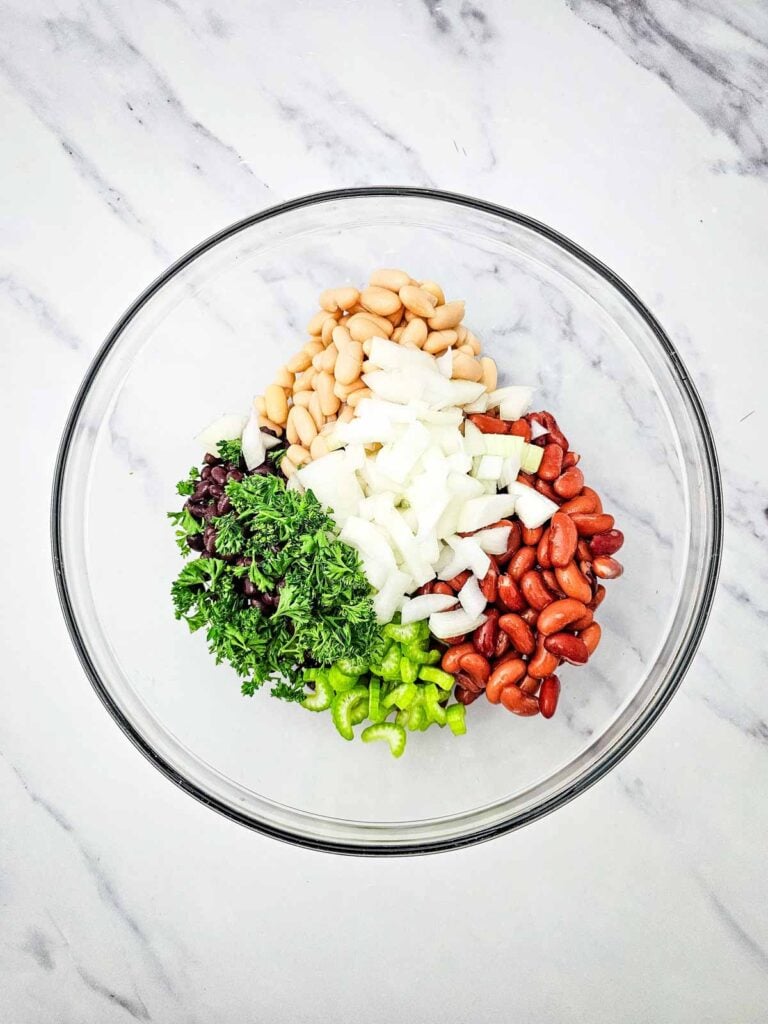 parsley, celery, diced onions and 3 kinds of beans in a glass mixing bowl