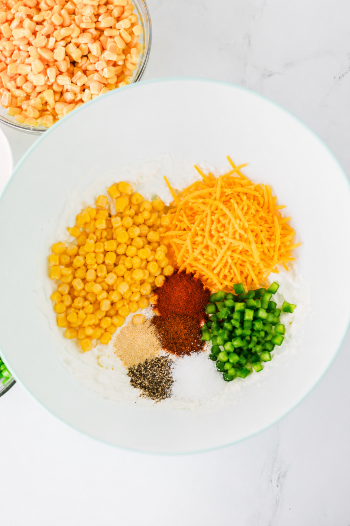 corn, shredded cheddar, diced jalapenos and spices in a mixing bowl