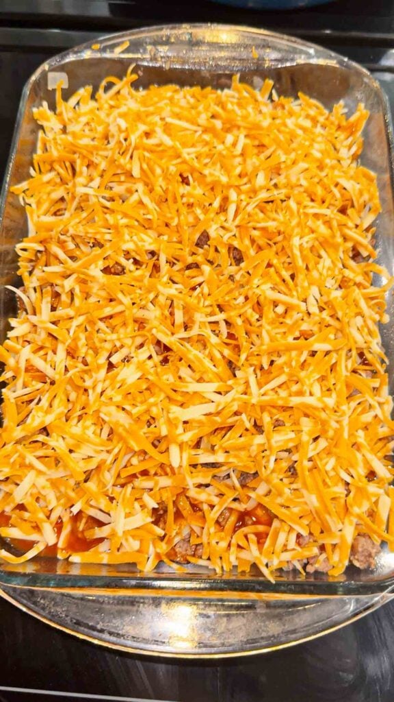 shredded cheddar cheese on top of ground beef and pierogies
