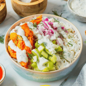 This Buffalo Chicken Bowl is the ultimate easy dinner recipe for busy weeknights, meal prep lunches, and game day food cravings. Tender chicken tossed in spicy Buffalo sauce is served over fluffy white rice and topped with crisp celery, red onion, and a creamy homemade ranch dressing for the perfect balance of heat and freshness. If you're looking for healthy chicken bowl recipes, Buffalo chicken rice bowls, easy meal prep ideas, or quick family dinner recipes, this dish checks every box. Packed with protein, loaded with flavor, and ready in just 30 minutes, these Buffalo Chicken Bowls are a satisfying comfort food meal that feels restaurant-worthy while being simple enough to make at home any night of the week.