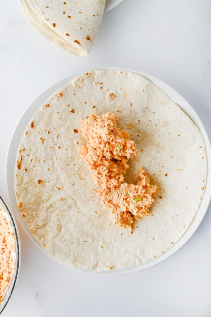 creamy buffalo chicken mixture spooned onto a flour tortilla