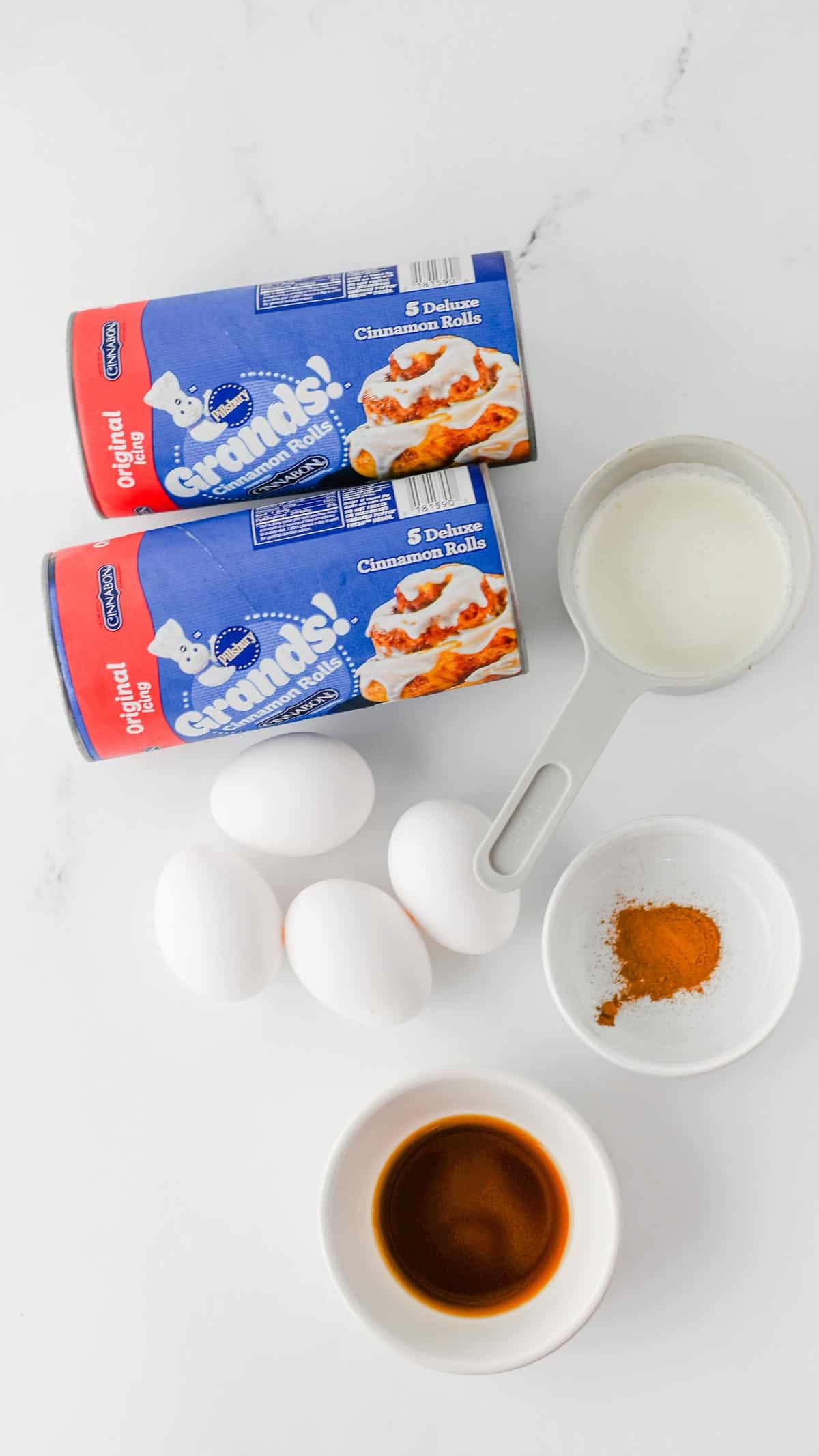pillsbury cinnamon roll tubes, eggs, vanilla extract, cinnamon and heavy cream on the kitchen counter