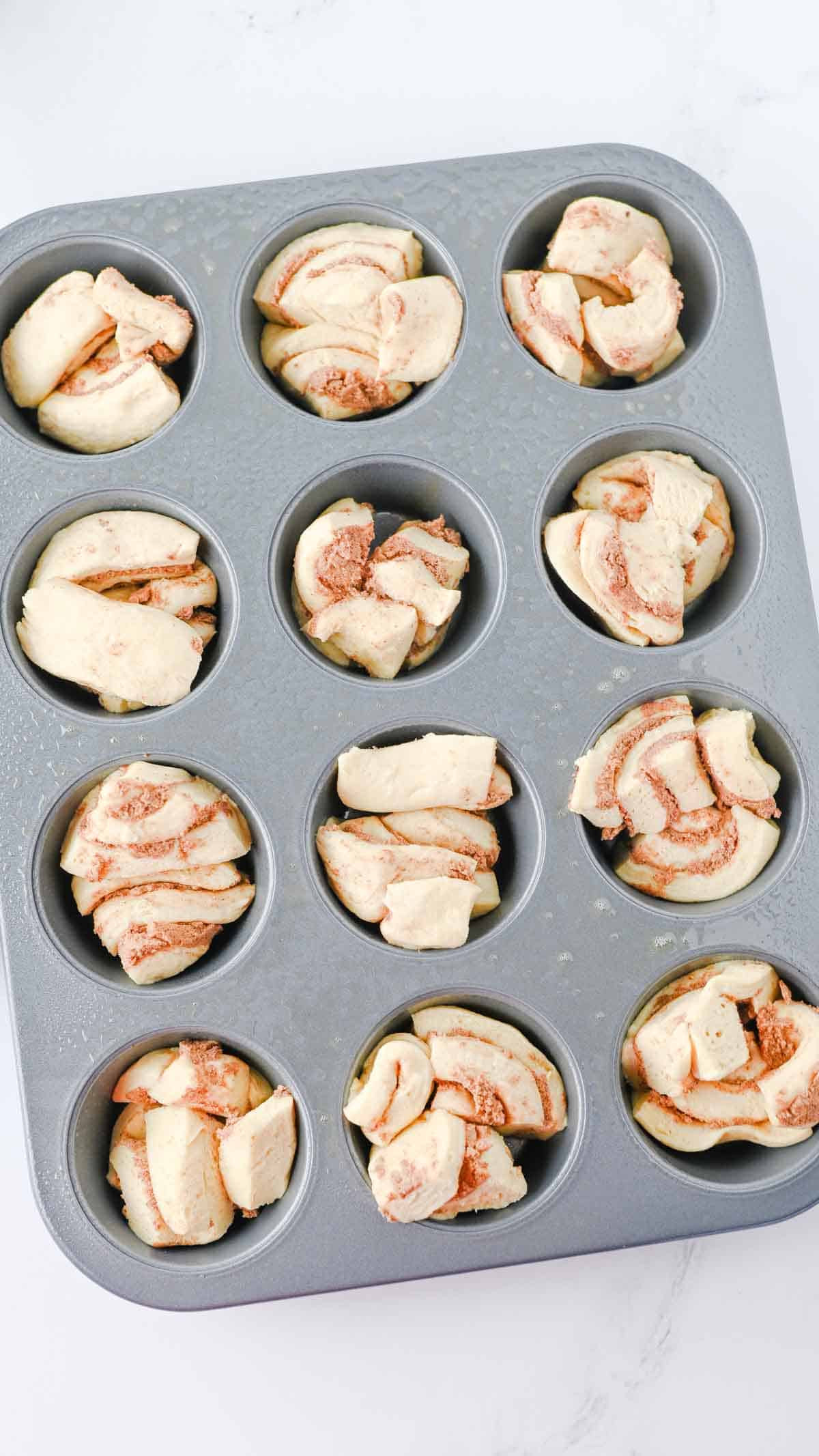 Pilsbury cinnamon roll chunks in a muffin tin