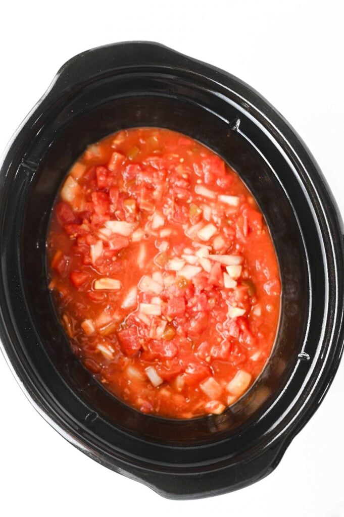 chicken enchilada ingredients stirred together in a slow cooker