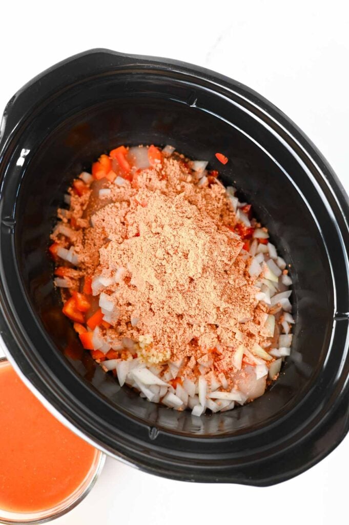 taco seasoning, onions, red bell peppers and raw chicken breasts in a slow cooker