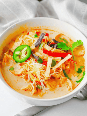 Warm up with this easy Crock Pot Chicken Tortilla Soup, a creamy and comforting dinner loaded with shredded chicken, black beans, pinto beans, corn, peppers, and bold Tex-Mex flavor. This Slow Cooker Chicken Tortilla Soup is the perfect dump-and-go meal for busy weeknights, meal prep, or cozy family dinners. Made with enchilada sauce, taco seasoning, and a splash of half and half, every spoonful is rich, hearty, and satisfying. Top it with crispy tortilla strips, shredded cheese, sour cream, avocado, or jalapeños for the ultimate bowl. If you're looking for easy crock pot soup recipes, slow cooker chicken recipes, or comforting fall and winter dinner ideas, this Chicken Tortilla Soup recipe is guaranteed to become a family favorite you'll make again and again.