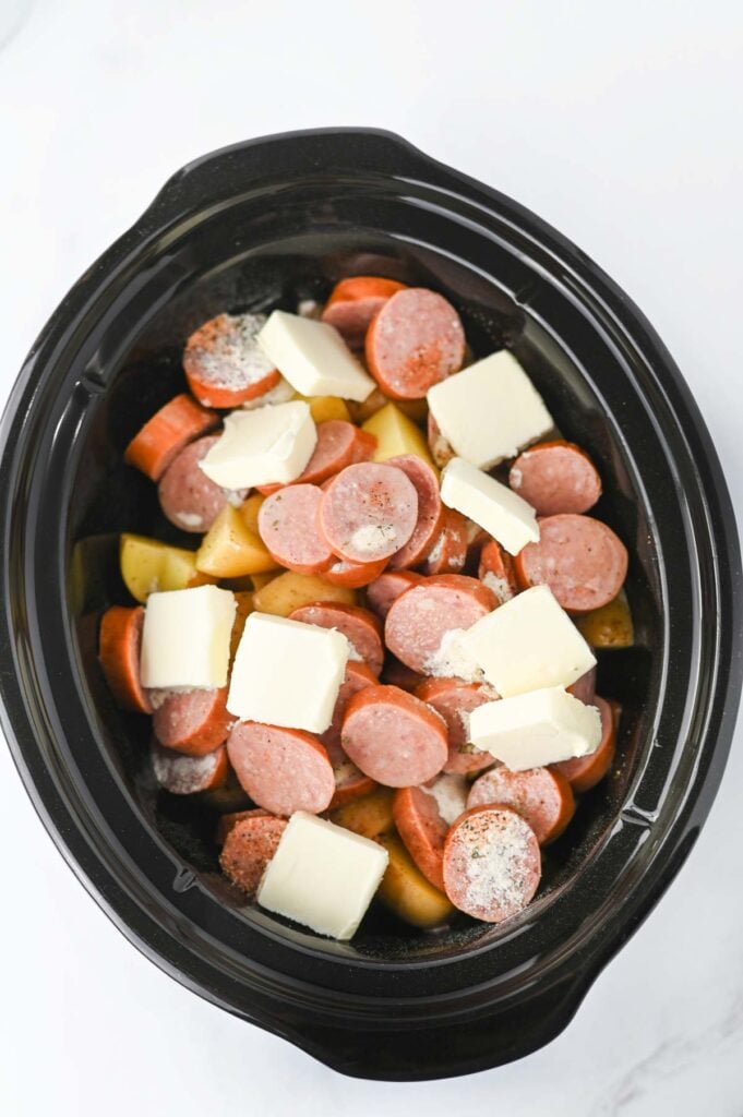butter, sausage slices and chopped potatoes in a slow cooker