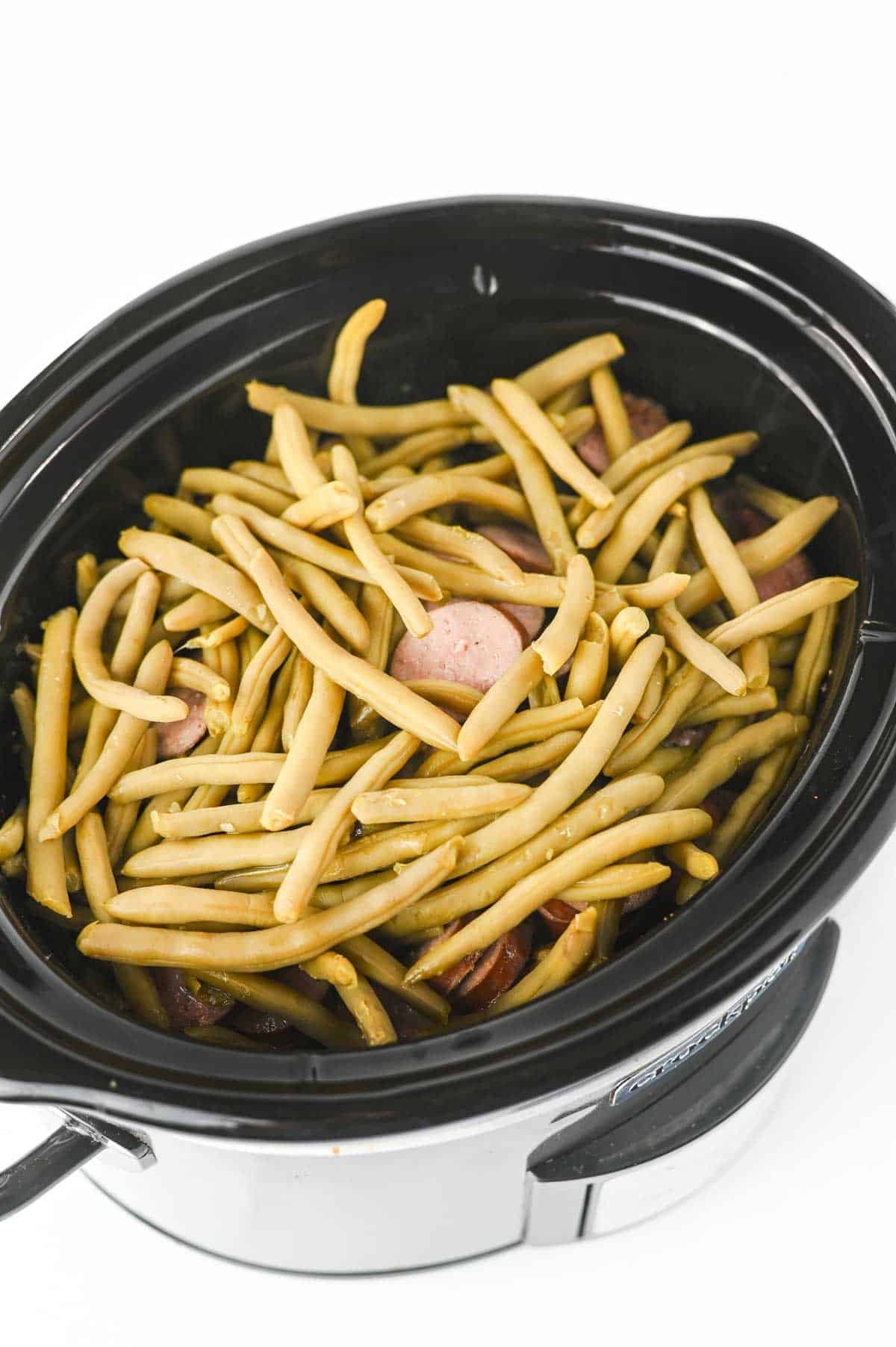 green beens on top of potatoes and sausage in a slow cooker