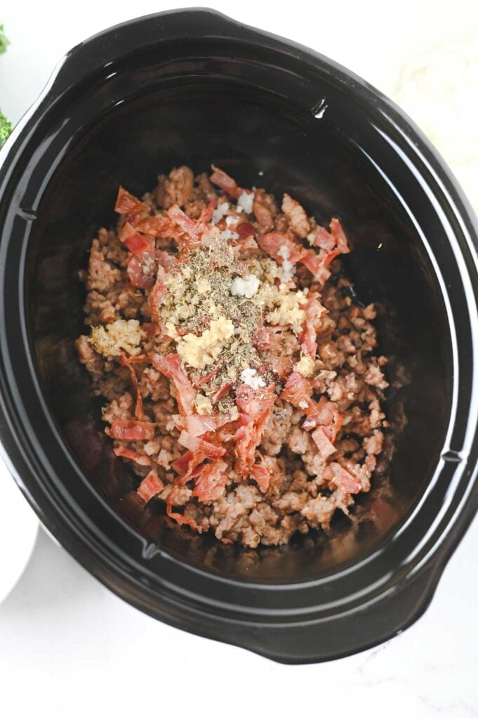 cooked and crumbled sausage, bacon and spices in a slow cooker