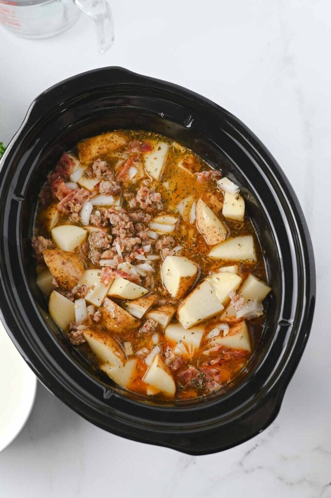 potato chunks and broth stirred into slow cooker with sausage meat