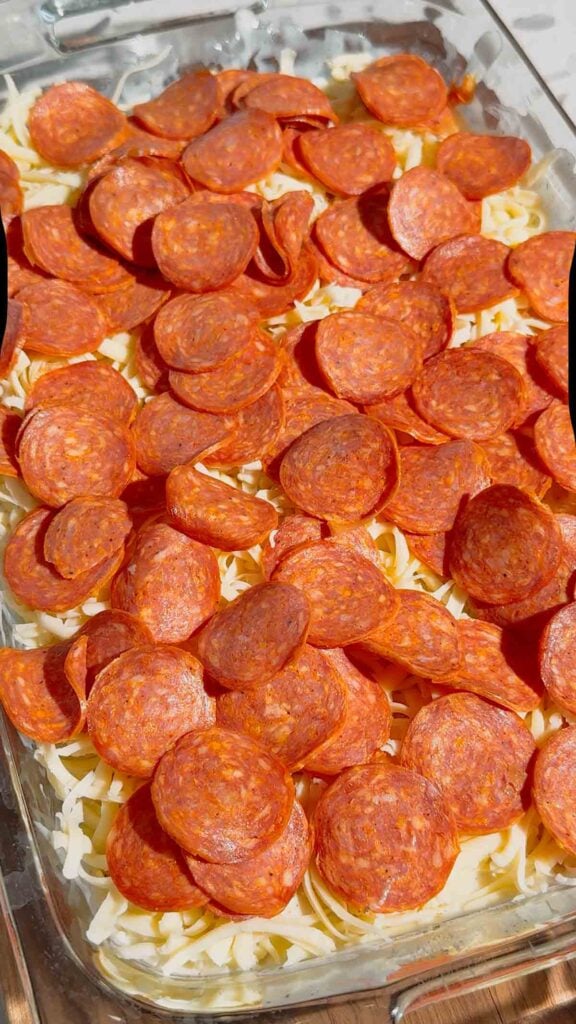 pepperoni slices on top of tortellini alfredo in a baking dish