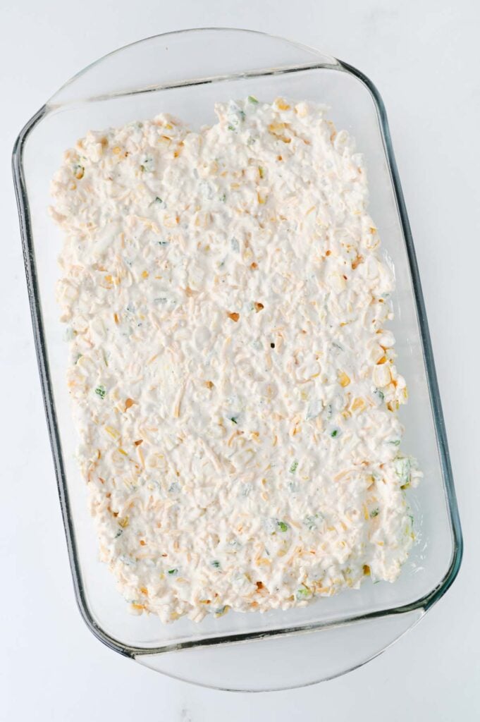 creamy corn dip spread out in a glass 9 x 13 inch baking dish