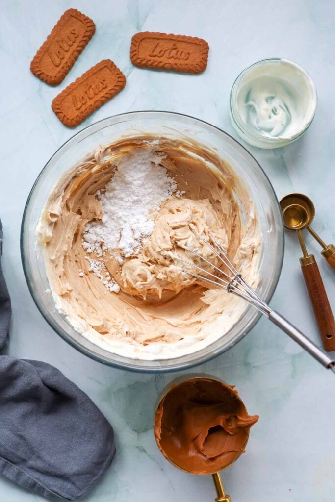 powdered sugar added to cream cheese mixture in a mixing bowl