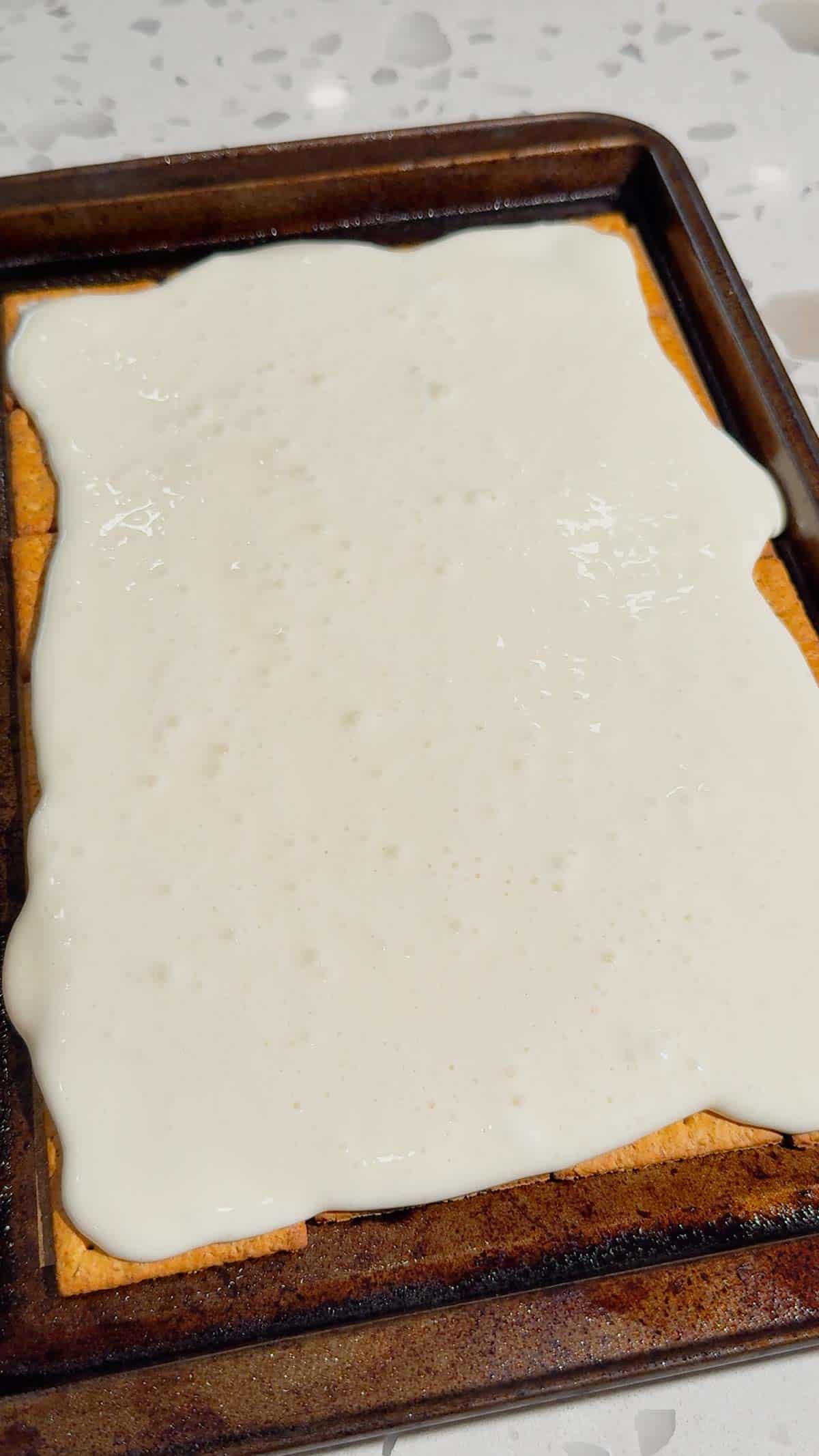 melted marshmallow mixture poured over graham crackers on a baking sheet