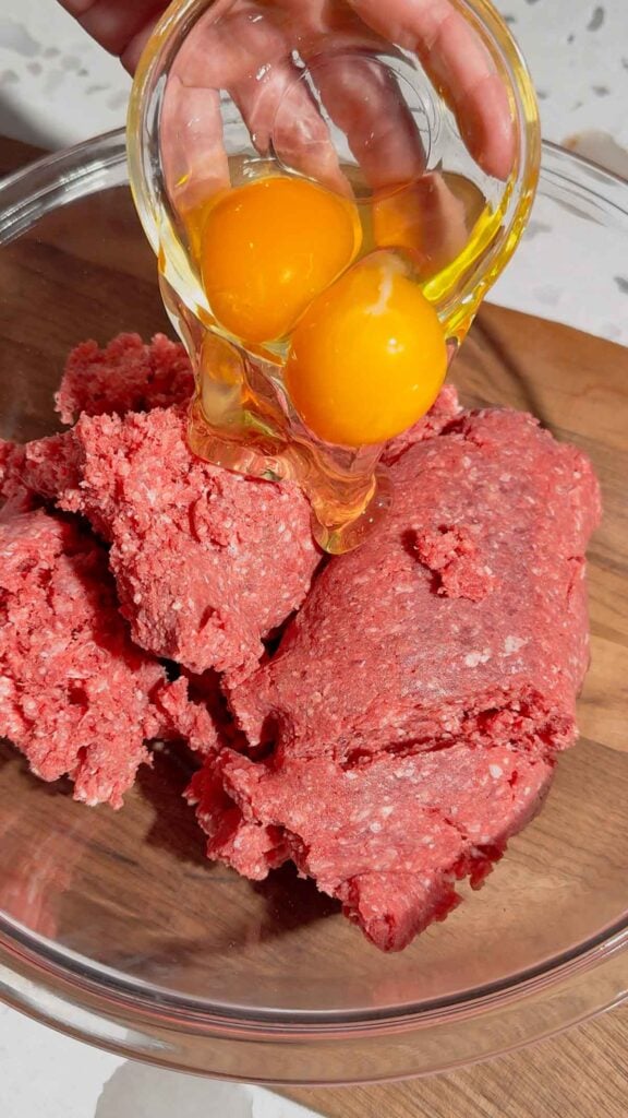 eggs added to bowl with raw ground beef