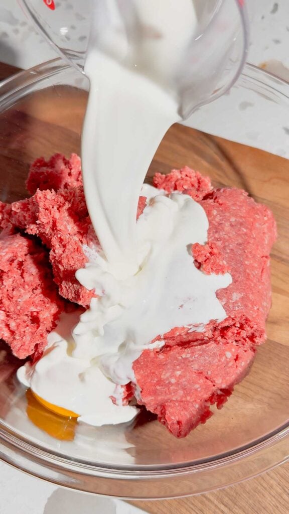 milk added to bowl with raw ground beef