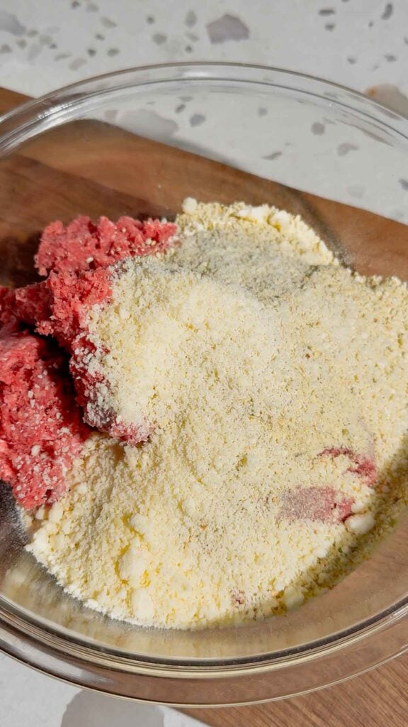 grated parmesan on top of bread crumbs and raw ground beef