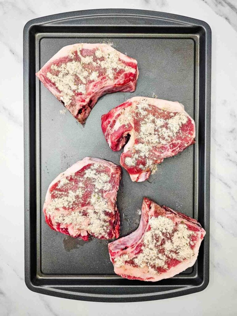 oiled and seasoned pork chops on a sheet pan
