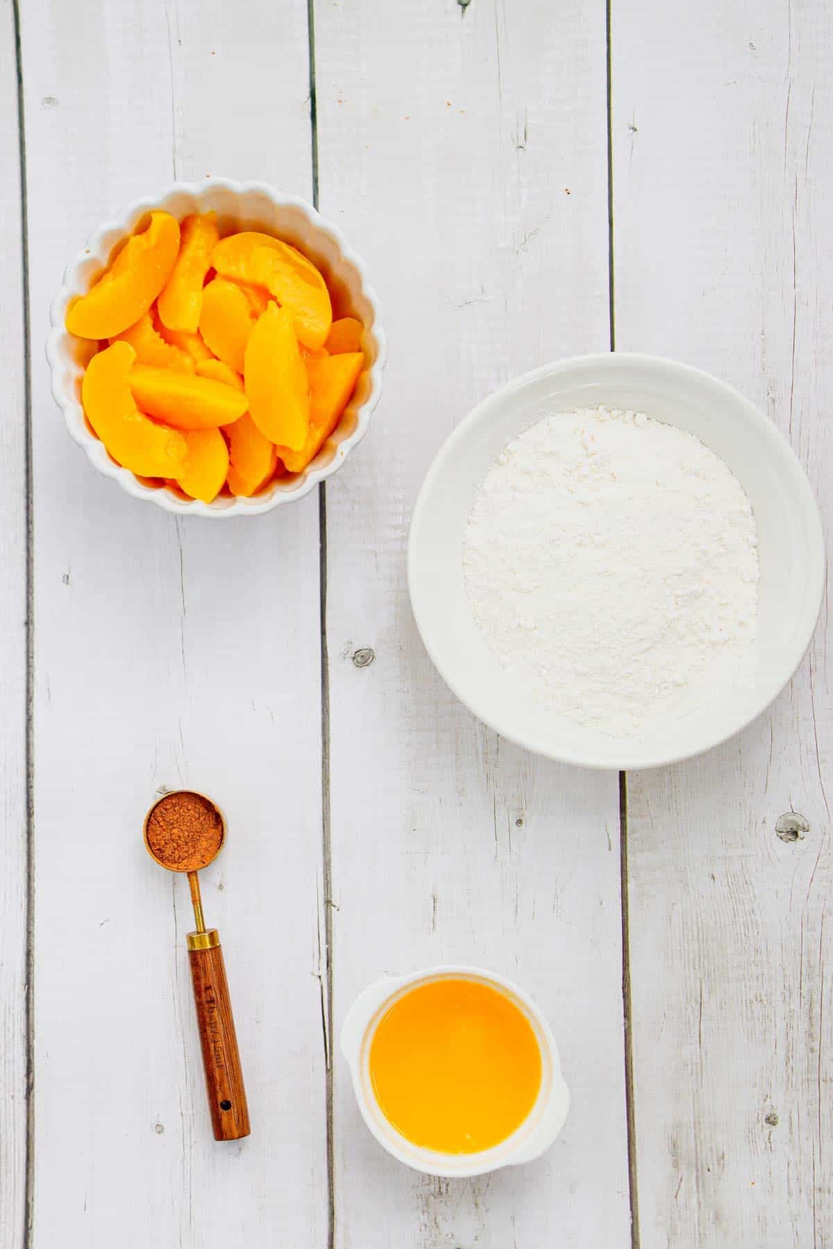 canned peaches, cake mix, melted butter and cinnamon on a kitchen counter