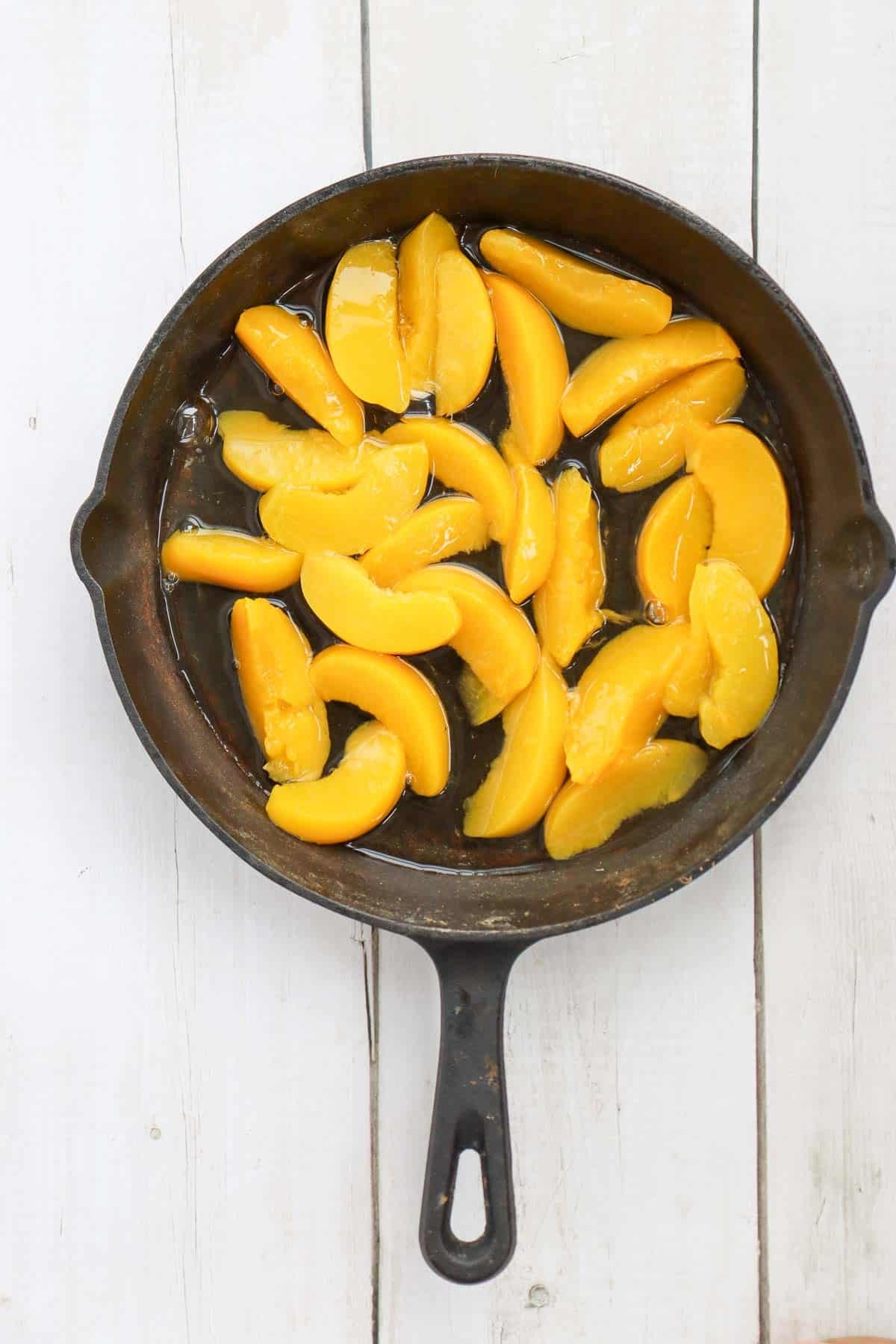 canned peaches and syrup poured into a cast iron skillet