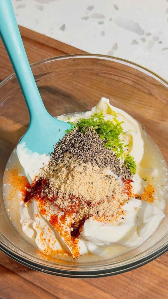 spices, lime zest, lime juice, mayo and sour cream in glass mixing bowl