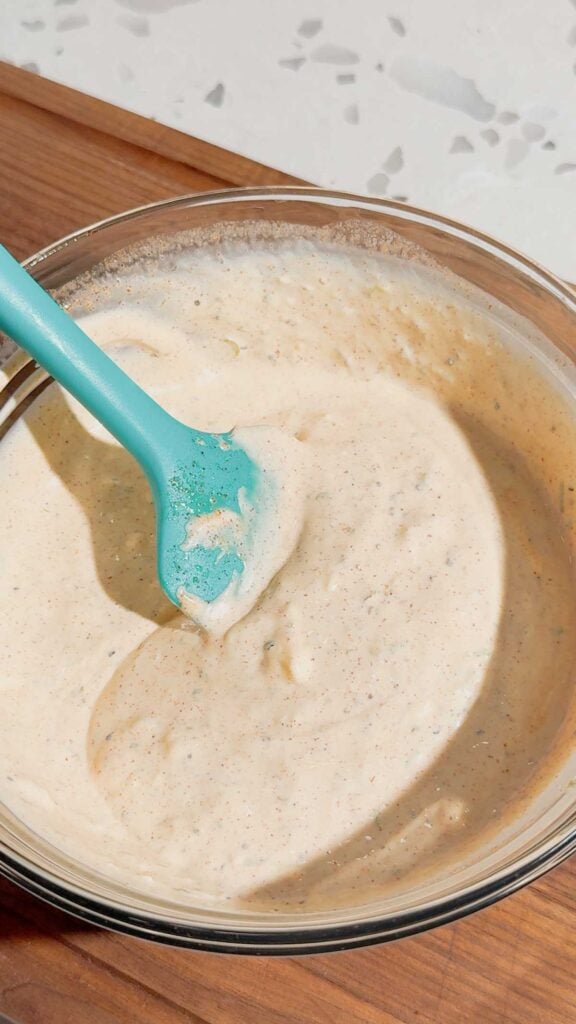 stirring creamy dressing in a glass mixing bowl