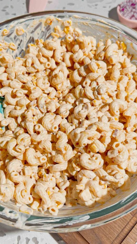 pasta and corn tossed in creamy dressing in a mixing bowl