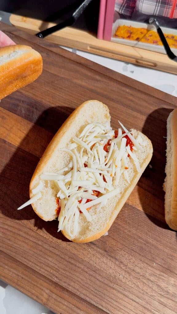 shredded mozzarella cheese on a hot dog bun