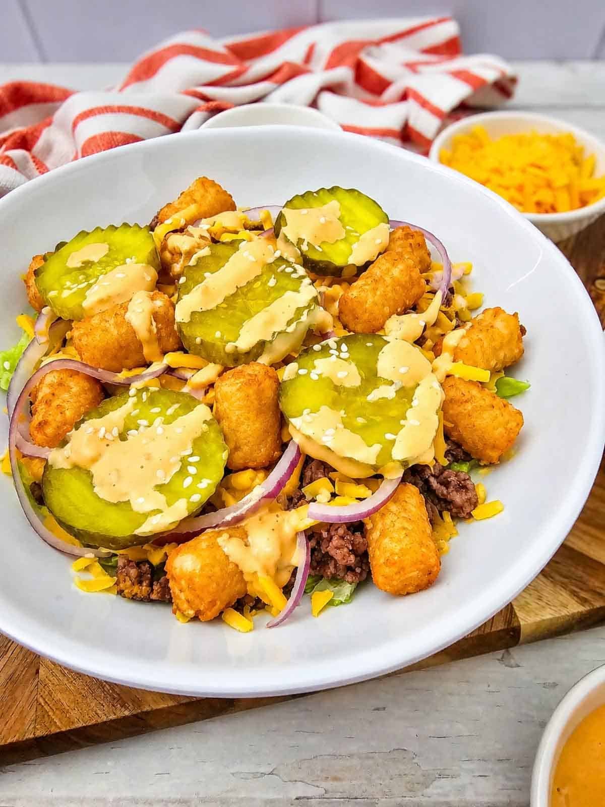 Craving all the flavors of your favorite fast food burger without the bun? This Big Mac Bowl is loaded with seasoned ground beef, crispy tater tots, shredded lettuce, cheddar cheese, red onion, pickles, sesame seeds, and a creamy special sauce for an easy meal the whole family will love. If you're looking for Big Mac Bowl Recipe, Burger Bowl Recipe, Cheeseburger Bowl, Low Carb Big Mac Bowl, Big Mac Salad Bowl, Ground Beef Dinner Ideas, Easy Ground Beef Recipes, Big Mac Casserole Inspiration, Burger Salad Recipe, or Quick Weeknight Dinners, this simple recipe is packed with classic burger flavor, comes together in under 20 minutes, and is perfect for busy nights, meal prep, or an easy comfort food dinner everyone will request again and again.