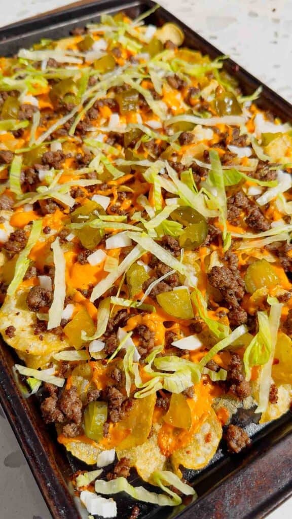 Looking for the ultimate game day snack or easy party appetizer? These Big Mac Nachos combine all the iconic flavors of your favorite cheeseburger with crispy kettle cooked potato chips for an unforgettable crowd-pleasing recipe. Loaded with seasoned ground beef, melted cheddar cheese, pickles, onions, shredded lettuce, Thousand Island dressing, and sesame seeds, these cheeseburger nachos are perfect for football parties, tailgates, family movie nights, and quick weeknight dinners. If you love loaded nachos, burger recipes, Big Mac-inspired recipes, easy appetizers, sheet pan snacks, comfort food, and fun party food ideas, this simple recipe belongs on your menu. Save this easy Big Mac Nachos recipe for your next game day spread, potluck, or casual family gathering!