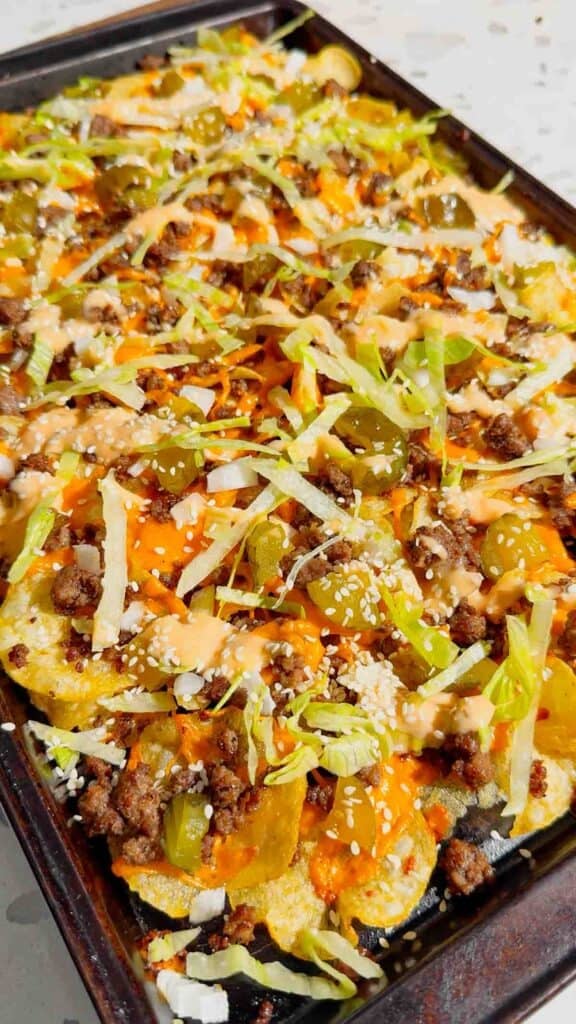 Looking for the ultimate game day snack or easy party appetizer? These Big Mac Nachos combine all the iconic flavors of your favorite cheeseburger with crispy kettle cooked potato chips for an unforgettable crowd-pleasing recipe. Loaded with seasoned ground beef, melted cheddar cheese, pickles, onions, shredded lettuce, Thousand Island dressing, and sesame seeds, these cheeseburger nachos are perfect for football parties, tailgates, family movie nights, and quick weeknight dinners. If you love loaded nachos, burger recipes, Big Mac-inspired recipes, easy appetizers, sheet pan snacks, comfort food, and fun party food ideas, this simple recipe belongs on your menu. Save this easy Big Mac Nachos recipe for your next game day spread, potluck, or casual family gathering!