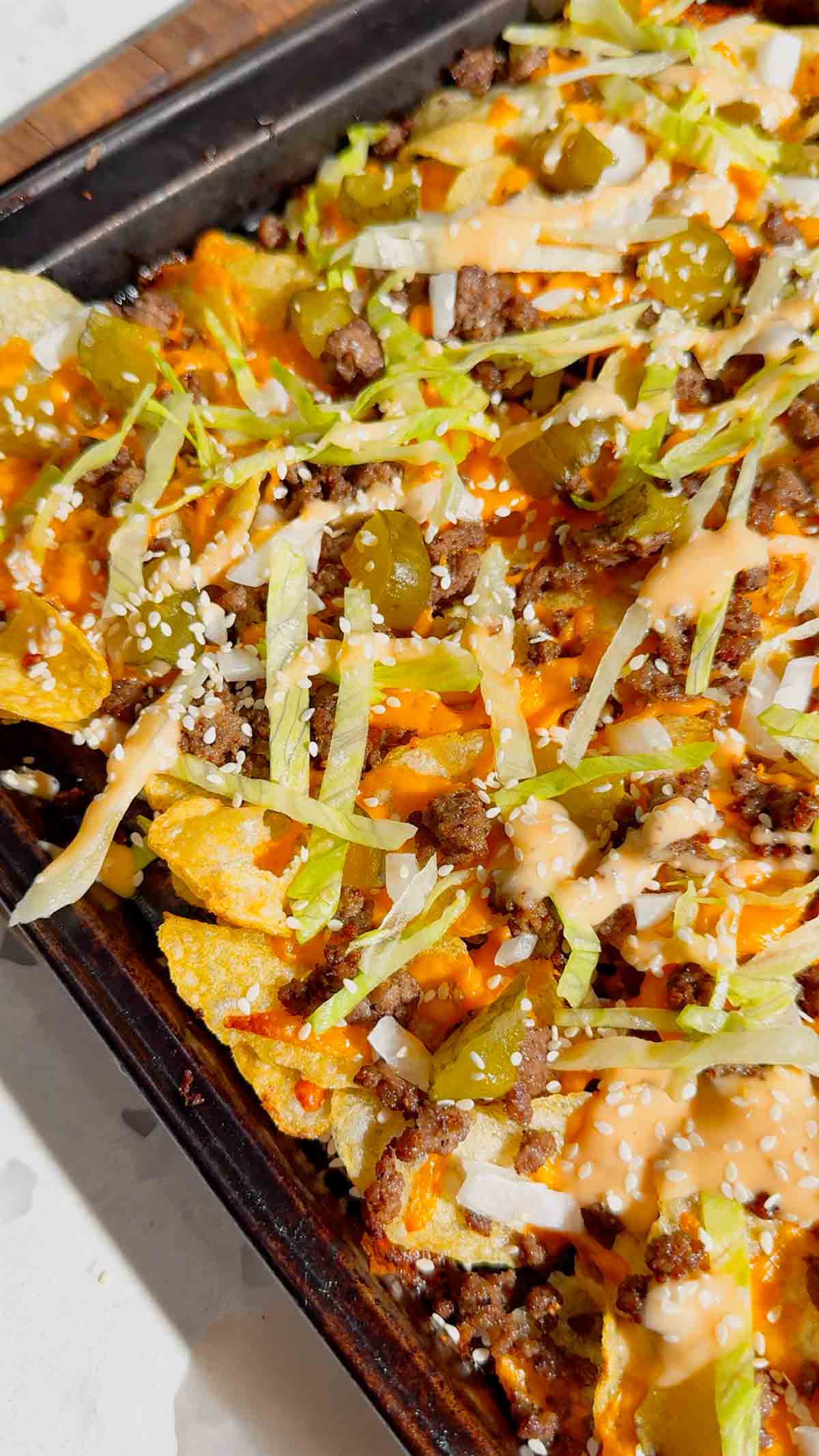 Looking for the ultimate game day snack or easy party appetizer? These Big Mac Nachos combine all the iconic flavors of your favorite cheeseburger with crispy kettle cooked potato chips for an unforgettable crowd-pleasing recipe. Loaded with seasoned ground beef, melted cheddar cheese, pickles, onions, shredded lettuce, Thousand Island dressing, and sesame seeds, these cheeseburger nachos are perfect for football parties, tailgates, family movie nights, and quick weeknight dinners. If you love loaded nachos, burger recipes, Big Mac-inspired recipes, easy appetizers, sheet pan snacks, comfort food, and fun party food ideas, this simple recipe belongs on your menu. Save this easy Big Mac Nachos recipe for your next game day spread, potluck, or casual family gathering!