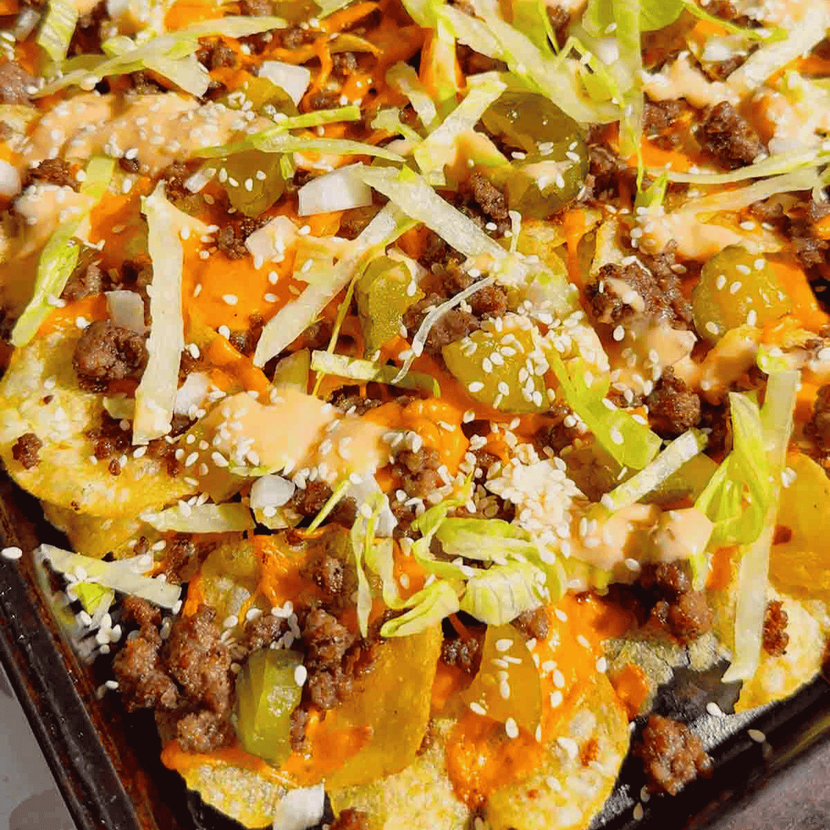 Looking for the ultimate game day snack or easy party appetizer? These Big Mac Nachos combine all the iconic flavors of your favorite cheeseburger with crispy kettle cooked potato chips for an unforgettable crowd-pleasing recipe. Loaded with seasoned ground beef, melted cheddar cheese, pickles, onions, shredded lettuce, Thousand Island dressing, and sesame seeds, these cheeseburger nachos are perfect for football parties, tailgates, family movie nights, and quick weeknight dinners. If you love loaded nachos, burger recipes, Big Mac-inspired recipes, easy appetizers, sheet pan snacks, comfort food, and fun party food ideas, this simple recipe belongs on your menu. Save this easy Big Mac Nachos recipe for your next game day spread, potluck, or casual family gathering!