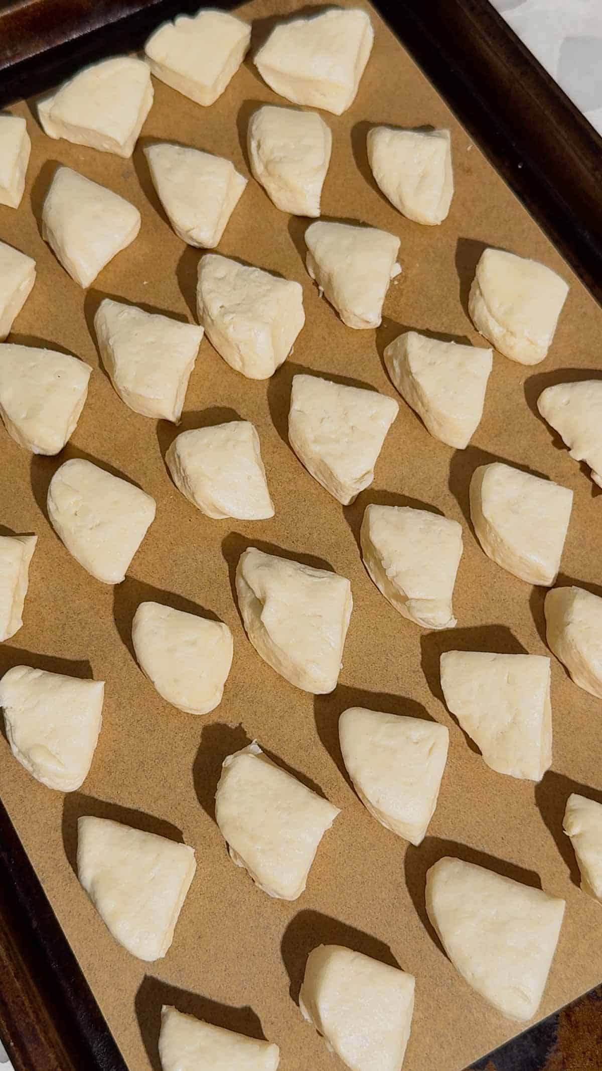 biscuit dough quarters on a parchment lined baking sheet