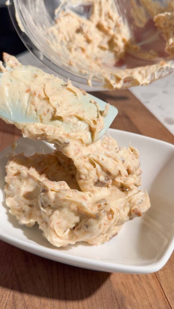 scooping butterfinger dip into a serving bowl