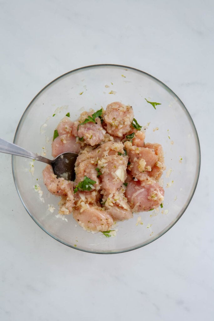 chicken chunks tossed in seasoning in a glass bowl