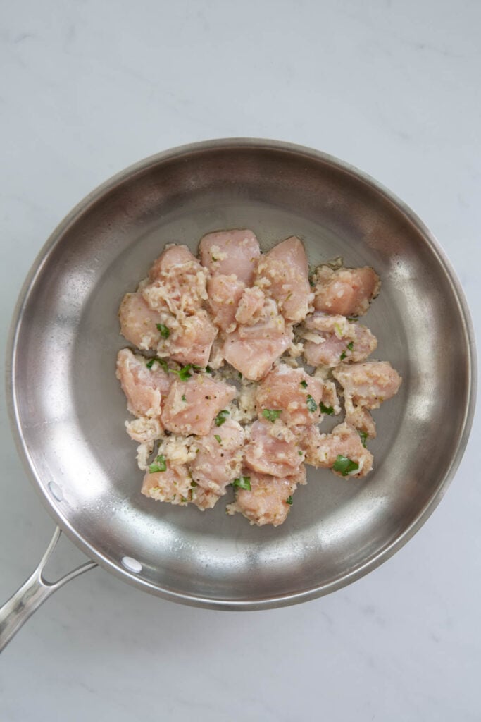 raw seasoned chicken breast chunks in a skillet