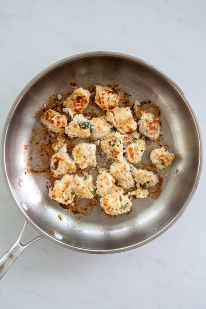 seasoned chicken breast chunks being browned in a skillet