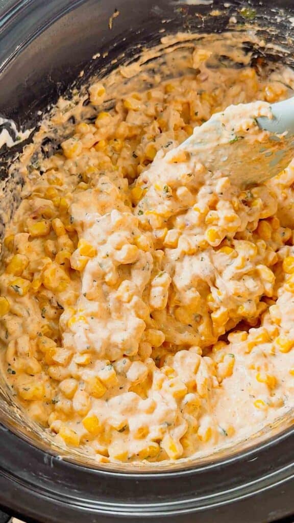 stirring hot street corn dip in a slow cooker
