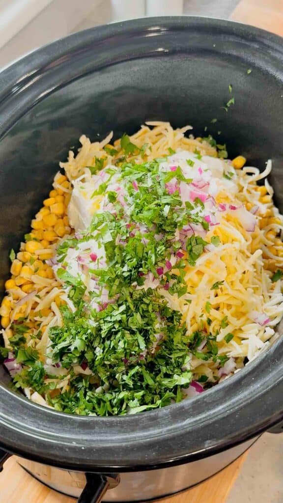 cilantro, shredded cheese, sour cream, cream cheese and corn in a slow cooker