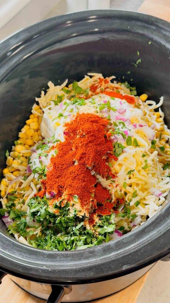 seasonings, cilantro, sour cream, shredded cheese and frozen corn in a slow cooker